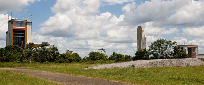 613 Ariane 5 is shown during its transfer from the Launcher Assembly Building (visible in the background at right) as it moves toward the Final Assembly Building (at left). This vehicle will be used for the fourth of seven Arianespace missions planned in 2009 with Ariane 5s.