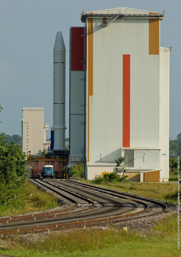 616_2_lg The first of two solid propellant boosters for the fifth Ariane 5 of 2009 begins the rollout process from its production and assembly zone at the Spaceport. The booster is built up on a pallet that is transferred via the facility’s rail system to the Launcher Integration Building, where it is integrated on the Ariane 5’s mobile launch table.