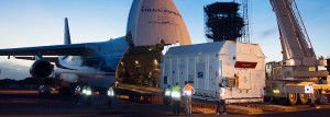 mission-up_634-panoramic Protected by its environmentally-controlled shipping container, COMSATBw-1 is unloaded from the An-124 cargo jetliner that brought this German military satellite to French Guiana.