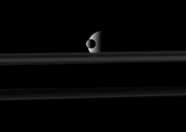 The small moon Mimas passes in front of the larger moon Rhea, which is partly obscured by Saturn's rings, in this movie from NASA’s Cassini spacecraft. Credit: NASA The small moon Mimas passes in front of the larger moon Rhea, which is partly obscured by Saturn's rings, in this movie from NASA’s Cassini spacecraft. Credit: NASA