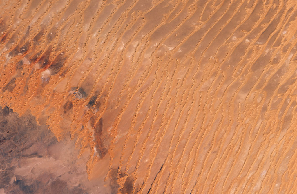 Vast, windswept plains of sand dunes (ergs), occasionally interrupted by rocky outcrops, stretch across much of Algeria in a giant C-shape. Credit: NASA Vast, windswept plains of sand dunes (ergs), occasionally interrupted by rocky outcrops, stretch across much of Algeria in a giant C-shape. Credit: NASA