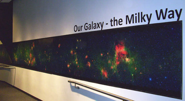 The world's largest image of our Milky Way galaxy, taken by NASA's Spitzer Space Telescope, went on display this week at the Adler Planetarium in Chicago. It is 120 feet long and 3 feet wide at its sides, bulging to about 6 feet wide at the center of our galaxy. Credit: Adler Planetarium The world's largest image of our Milky Way galaxy, taken by NASA's Spitzer Space Telescope, went on display this week at the Adler Planetarium in Chicago. It is 120 feet long and 3 feet wide at its sides, bulging to about 6 feet wide at the center of our galaxy. Credit: Adler Planetarium