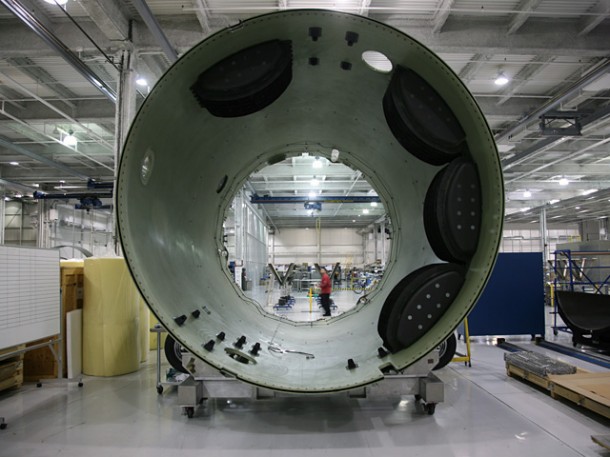 Looking “upwards” through the interstage for Falcon 9 Flight 2, shown undergoing final assembly in California. The four black containers will house the parachutes that will help return the first stage to Earth after stage separation. Credit: SpaceX. Looking “upwards” through the interstage for Falcon 9 Flight 2, shown undergoing final assembly in California. The four black containers will house the parachutes that will help return the first stage to Earth after stage separation. Credit: SpaceX.
