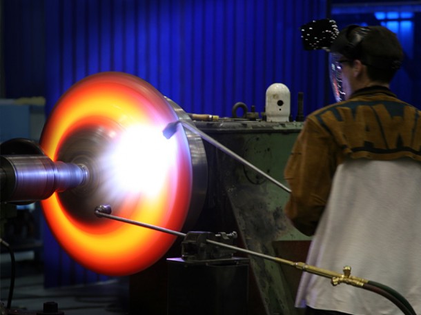 Spin-forming titanium sheet material into hemispheres. With a melting point of 1725 °C (3135 °F), we heat the metal to its plastic deformation point. Then a large metal wheel presses the softened metal around a steel hemisphere. Credit: SpaceX / Roger Gilbertson. Spin-forming titanium sheet material into hemispheres. With a melting point of 1725 °C (3135 °F), we heat the metal to its plastic deformation point. Then a large metal wheel presses the softened metal around a steel hemisphere. Credit: SpaceX / Roger Gilbertson.