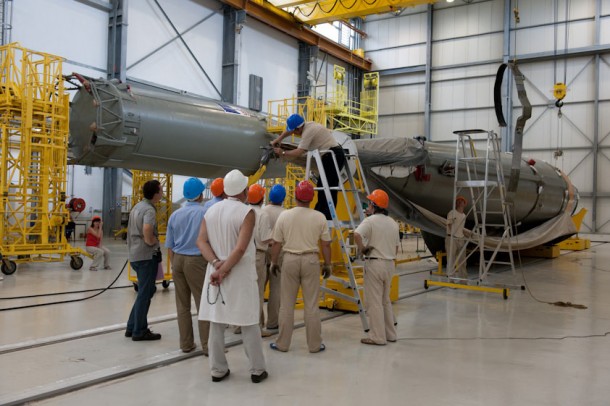 Soyuz’ first strap-on booster is at the center of attention as a team member removes the protective covering following its installation on a purpose-built jig. The launcher’s assembly is facilitated by a ground-based rail system, which enables the various elements to be positioned during the build-up process. Partly visible in the background is the Block A core stage, which awaits the integration of its no. 1 strap-on booster. Soyuz’ first strap-on booster is at the center of attention as a team member removes the protective covering following its installation on a purpose-built jig. The launcher’s assembly is facilitated by a ground-based rail system, which enables the various elements to be positioned during the build-up process. Partly visible in the background is the Block A core stage, which awaits the integration of its no. 1 strap-on booster.