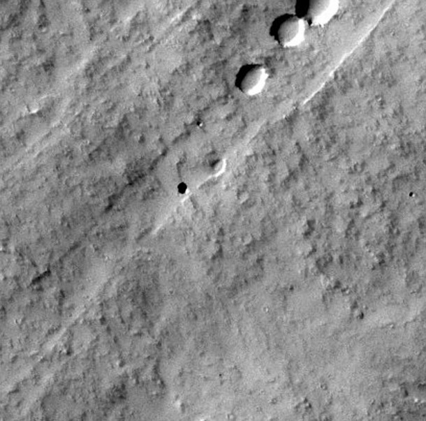 The small round black spot in this THEMIS image may be a hole in the roof of a Martian lava tube or cave. Credit: NASA The small round black spot in this THEMIS image may be a hole in the roof of a Martian lava tube or cave. Credit: NASA