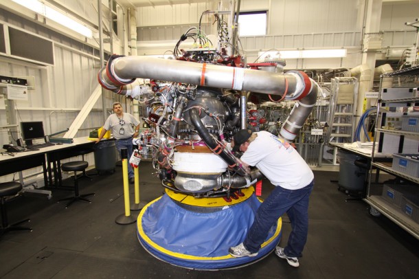 A technician examines a space shuttle main engine as it sits in a workstand. The top part of the engine is called the "powerhead" and it is the section of the machinery that houses turbopumps and the ductwork needed to generate the thrust to lift the space shuttle into orbit. Photo credit: NASA/Jack Pfaller A technician examines a space shuttle main engine as it sits in a workstand. The top part of the engine is called the "powerhead" and it is the section of the machinery that houses turbopumps and the ductwork needed to generate the thrust to lift the space shuttle into orbit. Photo credit: NASA/Jack Pfaller