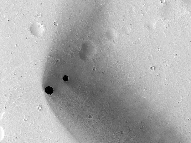 Two dark, rimless pits are located to the northwest of Ascraeus Mons in the Tharsis volcanic region of Mars. Image credit: NASA/JPL-Caltech/University of Arizona Two dark, rimless pits are located to the northwest of Ascraeus Mons in the Tharsis volcanic region of Mars. Image credit: NASA/JPL-Caltech/University of Arizona