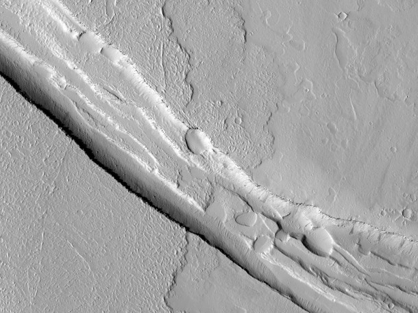This image shows a graben (a trough formed when the ground drops between two parallel faults) and a lava flow in the Tharsis volcanic province of Mars. Image credit: NASA/JPL-Caltech/University of Arizona