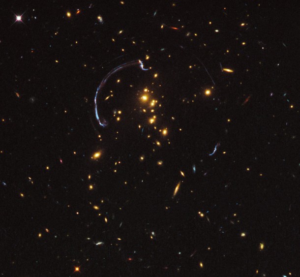 Thanks to the presence of a natural “zoom lens” in space, this is a close-up look at brightest distant “magnified” galaxy in the universe known to date. It is one of the most striking examples of gravitational lensing, where the gravitational field of a foreground galaxy bends and amplifies the light of a more distant background galaxy. In this image the light from a distant galaxy, nearly 10 billion light-years away, has been warped into a nearly 90-degree arc of light in the galaxy cluster RCS2 032727-132623. The galaxy cluster lies 5 billion light-years away. The background galaxy’s image is 20 times larger and over three times brighter than typically lensed galaxies. The natural color image was taken in March 2011 with the Hubble Space Telescope’s Wide Field Camera 3. Credit: NASA; ESA; J. Rigby (NASA Goddard Space Flight Center); and K. Sharon (Kavli Institute for Cosmological Physics, University of Chicago) Thanks to the presence of a natural “zoom lens” in space, this is a close-up look at brightest distant “magnified” galaxy in the universe known to date. It is one of the most striking examples of gravitational lensing, where the gravitational field of a foreground galaxy bends and amplifies the light of a more distant background galaxy. In this image the light from a distant galaxy, nearly 10 billion light-years away, has been warped into a nearly 90-degree arc of light in the galaxy cluster RCS2 032727-132623. The galaxy cluster lies 5 billion light-years away. The background galaxy’s image is 20 times larger and over three times brighter than typically lensed galaxies. The natural color image was taken in March 2011 with the Hubble Space Telescope’s Wide Field Camera 3. Credit: NASA; ESA; J. Rigby (NASA Goddard Space Flight Center); and K. Sharon (Kavli Institute for Cosmological Physics, University of Chicago)