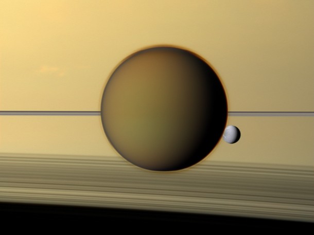 Saturn's third-largest moon Dione can be seen through the haze of its largest moon, Titan, in this view of the two posing before the planet and its rings from NASA's Cassini spacecraft. Image credit: NASA/JPL-Caltech/SSI Saturn's third-largest moon Dione can be seen through the haze of its largest moon, Titan, in this view of the two posing before the planet and its rings from NASA's Cassini spacecraft. Image credit: NASA/JPL-Caltech/SSI