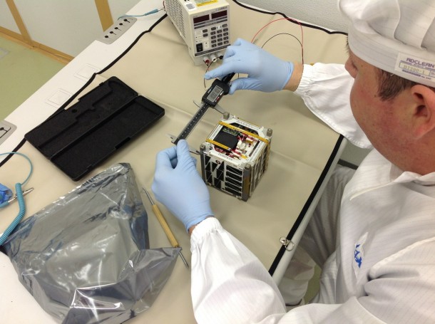 A laboratory technician does some very precise measurements on the tiny satellite. A laboratory technician does some very precise measurements on the tiny satellite.