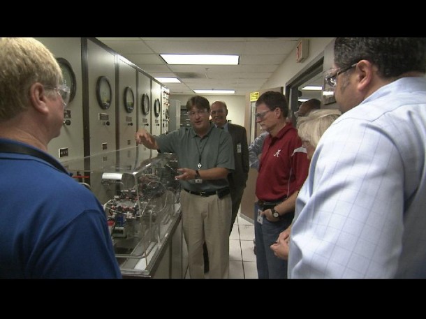 During a recent tour for Space Launch System Program managers, Mike Kynard, center, manager of the program's Engines element office, explains how test personnel use working parts from an RS-25 engine to test the new engine control unit at the Marshall Space Flight Center test facilities. (NASA/MSFC) During a recent tour for Space Launch System Program managers, Mike Kynard, center, manager of the program's Engines element office, explains how test personnel use working parts from an RS-25 engine to test the new engine control unit at the Marshall Space Flight Center test facilities. (NASA/MSFC)