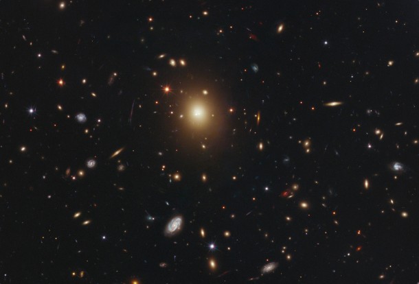 The giant elliptical galaxy in the center of this Hubble image is the most massive and brightest member of the galaxy cluster Abell 2261. Spanning a little more than one million light-years,the galaxy is about 10 times the diameter of our Milky Way galaxy. The bloated galaxy is a member of an unusual class of galaxies with a diffuse core filled with a fog of starlight. Abell 2261 is located three billion light-years away. The observations were taken March to May 2011. Credit: NASA; ESA; M. Postman, STScI; T. Lauer, NOAO, Tucson; CLASH team. The giant elliptical galaxy in the center of this Hubble image is the most massive and brightest member of the galaxy cluster Abell 2261. Spanning a little more than one million light-years,the galaxy is about 10 times the diameter of our Milky Way galaxy. The bloated galaxy is a member of an unusual class of galaxies with a diffuse core filled with a fog of starlight. Abell 2261 is located three billion light-years away. The observations were taken March to May 2011. Credit: NASA; ESA; M. Postman, STScI; T. Lauer, NOAO, Tucson; CLASH team.