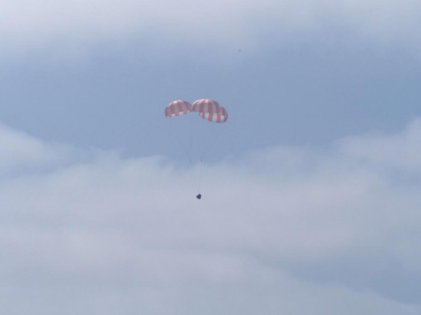 Dragon on its final descent to the Pacific Ocean, with three main parachutes slowing the spacecraft. Dragon on its final descent to the Pacific Ocean, with three main parachutes slowing the spacecraft.