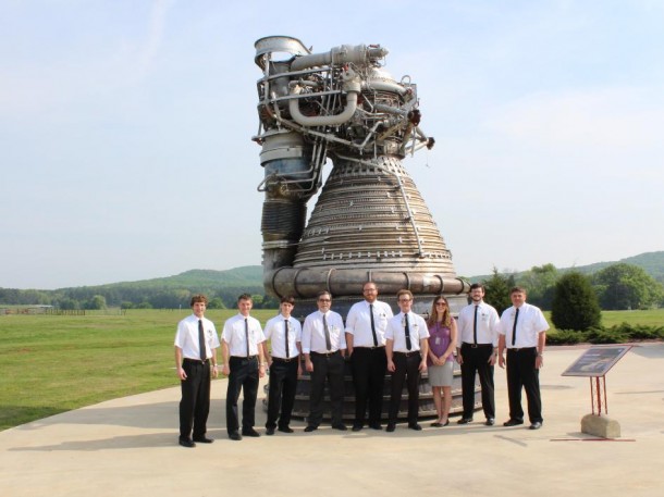 Engineers stand by a Saturn V F-1 engine. (NASA/MSFC) 