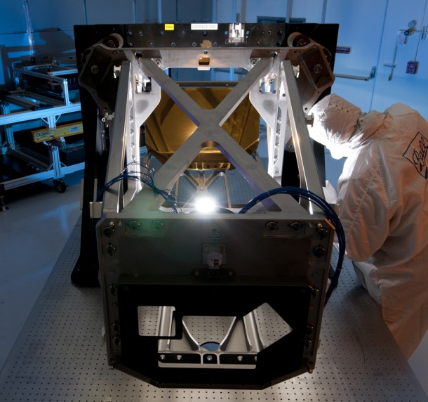 Ball Aerospace Technician Robin Russell inspects the Webb Telescope Aft Optics Subsystem during mirror integration activities. The Aft Optics bench, made of lightweight beryllium like the mirrors, holds Webb's tertiary and fine steering mirrors. The installed, gold-coated tertiary mirror can be seen in the background. Photo courtesy Ball Aerospace. Ball Aerospace Technician Robin Russell inspects the Webb Telescope Aft Optics Subsystem during mirror integration activities. The Aft Optics bench, made of lightweight beryllium like the mirrors, holds Webb's tertiary and fine steering mirrors. The installed, gold-coated tertiary mirror can be seen in the background. Photo courtesy Ball Aerospace.