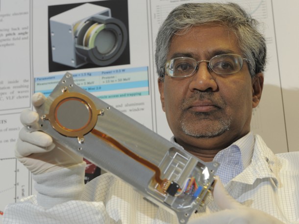 Scientist Shri Kanekal holds one of the solid-state detectors that will be used in the Compact Relativistic Electron and Proton Telescope (CREPT). The picture on the wall to the left is a design diagram of the instrument. Credit: NASA/ P. Izzo Scientist Shri Kanekal holds one of the solid-state detectors that will be used in the Compact Relativistic Electron and Proton Telescope (CREPT). The picture on the wall to the left is a design diagram of the instrument. Credit: NASA/ P. Izzo