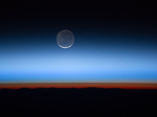 This image shows the moon, Earth's only natural satellite, at center with the limb of Earth near the bottom transitioning into the orange-colored troposphere, the lowest and most dense portion of Earth's atmosphere. The troposphere ends abruptly at the tropopause, which appears in the image as the sharp boundary between the orange- and blue-colored atmosphere. The silvery-blue noctilucent clouds extend far above Earth's troposphere. Image credit: NASA This image shows the moon, Earth's only natural satellite, at center with the limb of Earth near the bottom transitioning into the orange-colored troposphere, the lowest and most dense portion of Earth's atmosphere. The troposphere ends abruptly at the tropopause, which appears in the image as the sharp boundary between the orange- and blue-colored atmosphere. The silvery-blue noctilucent clouds extend far above Earth's troposphere. Image credit: NASA