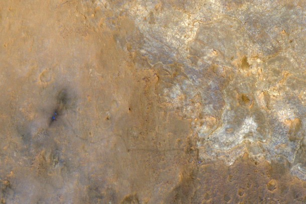 NASA's Mars Science Laboratory rover Curiosity appears as a bluish dot near the lower right corner of this enhanced-color view from the High Resolution Imaging Science Experiment (HiRISE) camera on NASA's Mars Reconnaissance Orbiter. The rover's tracks are visible extending from the landing site, "Bradbury Landing," in the left half of the scene. Two bright, relatively blue spots surrounded by darker patches are where the Mars Science Laboratory spacecraft's landing jets cleared away reddish surface dust at the landing site. North is toward the top. For scale, the two parallel lines of the wheel tracks are about 10 feet (3 meters) apart. Image credit: NASA/JPL-Caltech/Univ. of Arizona NASA's Mars Science Laboratory rover Curiosity appears as a bluish dot near the lower right corner of this enhanced-color view from the High Resolution Imaging Science Experiment (HiRISE) camera on NASA's Mars Reconnaissance Orbiter. The rover's tracks are visible extending from the landing site, "Bradbury Landing," in the left half of the scene. Two bright, relatively blue spots surrounded by darker patches are where the Mars Science Laboratory spacecraft's landing jets cleared away reddish surface dust at the landing site. North is toward the top. For scale, the two parallel lines of the wheel tracks are about 10 feet (3 meters) apart. Image credit: NASA/JPL-Caltech/Univ. of Arizona
