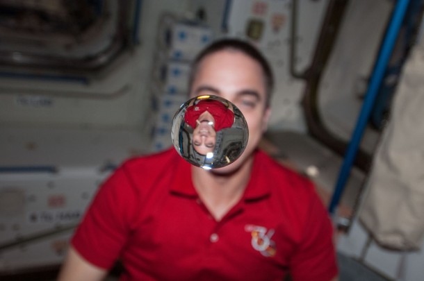 Flight Engineer Chris Cassidy watches a water bubble float freely between him and the camera, showing his image refracted, in the Unity node of the International Space Station. Image Credit: NASA Flight Engineer Chris Cassidy watches a water bubble float freely between him and the camera, showing his image refracted, in the Unity node of the International Space Station. Image Credit: NASA