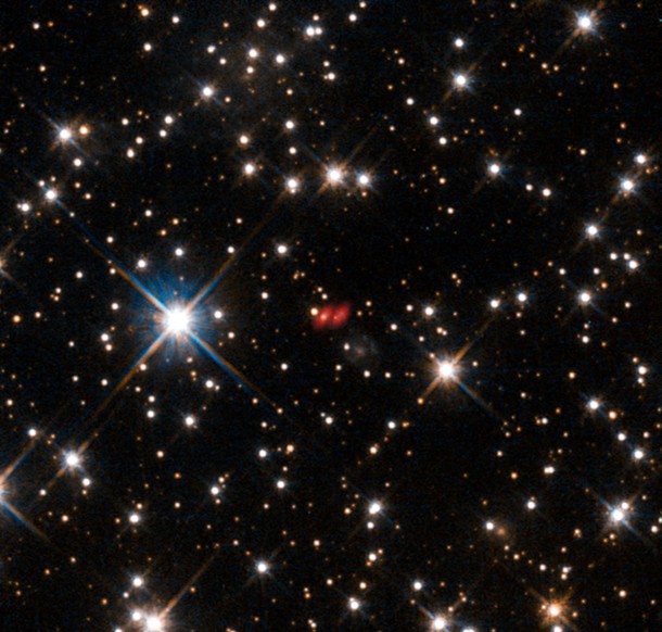 This image from the NASA/ESA Hubble Space Telescope shows the distant active galaxy PKG 1830-211. It shows up as an unremarkable looking star-like object, hard to spot among the many much closer real stars in this picture. Recent ALMA observations show both components of this distant gravitational lens and are marked in red on this composite picture. Credit: ALMA (ESO/NAOJ/NRAO)/NASA/ESA/I. Martí-Vidal This image from the NASA/ESA Hubble Space Telescope shows the distant active galaxy PKG 1830-211. It shows up as an unremarkable looking star-like object, hard to spot among the many much closer real stars in this picture. Recent ALMA observations show both components of this distant gravitational lens and are marked in red on this composite picture. Credit: ALMA (ESO/NAOJ/NRAO)/NASA/ESA/I. Martí-Vidal