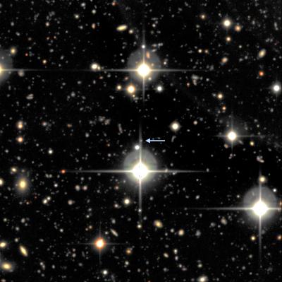 A small portion of one of the fields from the Supernova Legacy Survey showing SNLS-06D4eu and its host galaxy (arrow). The supernova and its host galaxy are so far away that both are a tiny point of light that cannot be clearly differentiated in this image. The large, bright objects with spikes are stars in our own galaxy. Every other point of light is a distant galaxy. Credit: UCSB A small portion of one of the fields from the Supernova Legacy Survey showing SNLS-06D4eu and its host galaxy (arrow). The supernova and its host galaxy are so far away that both are a tiny point of light that cannot be clearly differentiated in this image. The large, bright objects with spikes are stars in our own galaxy. Every other point of light is a distant galaxy. Credit: UCSB