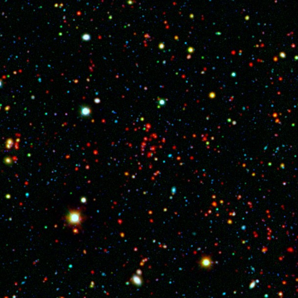 The collection of red dots seen near the center of this image show one of several very distant galaxy clusters discovered by combining ground-based optical data from the National Optical Astronomy Observatory's Kitt Peak National Observatory with infrared data from NASA's Spitzer Space Telescope. This galaxy cluster, named ISCS J1434.7+3519, is located about 9 billion light-years from Earth. Image credit: NASA/JPL-Caltech/KPNO/University of Missouri-Kansas City The collection of red dots seen near the center of this image show one of several very distant galaxy clusters discovered by combining ground-based optical data from the National Optical Astronomy Observatory's Kitt Peak National Observatory with infrared data from NASA's Spitzer Space Telescope. This galaxy cluster, named ISCS J1434.7+3519, is located about 9 billion light-years from Earth. Image credit: NASA/JPL-Caltech/KPNO/University of Missouri-Kansas City