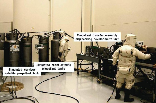 During testing on Sept. 17, 2013, a NASA engineer participating on Kennedy's satellite servicing team, on the right, operates an engineering development unit that mimics a servicing satellite's propellant transfer system. A Jacobs Technology technician, on the left, monitors progress as nitrogen tetroxide is pumped from two containers representing a servicing satellite into containers simulating a client spacecraft. Both participants are wearing protective gear called Self-Contained Atmospheric Protective Ensembles, or SCAPE suits. Image Credit: NASA During testing on Sept. 17, 2013, a NASA engineer participating on Kennedy's satellite servicing team, on the right, operates an engineering development unit that mimics a servicing satellite's propellant transfer system. A Jacobs Technology technician, on the left, monitors progress as nitrogen tetroxide is pumped from two containers representing a servicing satellite into containers simulating a client spacecraft. Both participants are wearing protective gear called Self-Contained Atmospheric Protective Ensembles, or SCAPE suits. Image Credit: NASA