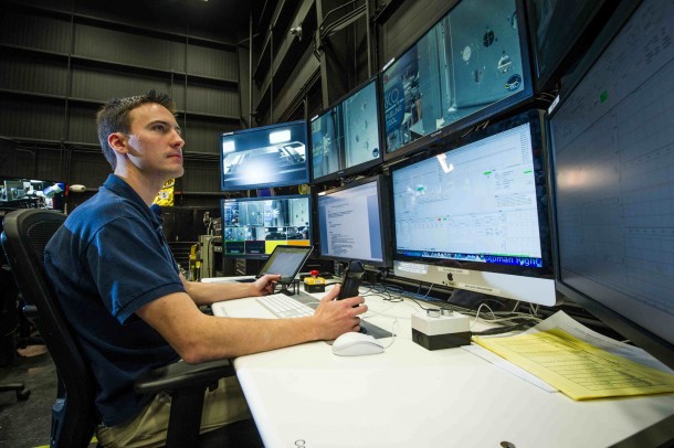 From his control center at NASA Goddard, RROxiTT lead roboticist Alex Janas commands an industrial robot more than 800 miles away at Kennedy Space Center (robot shown here, right, at NASA Goddard before it was shipped to Kennedy). Image Credit: NASA/Chris Gunn From his control center at NASA Goddard, RROxiTT lead roboticist Alex Janas commands an industrial robot more than 800 miles away at Kennedy Space Center (robot shown here, right, at NASA Goddard before it was shipped to Kennedy). Image Credit: NASA/Chris Gunn