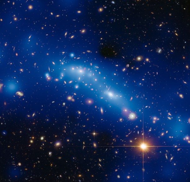 The varying intensity of blue haze in this image is a mass map created by using new Hubble observations combined with the magnifying power of a process known as gravitational lensing. Strong lensing gives a much more precise indication of the mass at the cluster’s core whilst weak lensing provides valuable information about the mass surrounding the cluster core. Credit: ESA/Hubble, NASA, HST Frontier Fields Acknowledgement: Mathilde Jauzac (Durham University, UK and Astrophysics & Cosmology Research Unit, South Africa) and Jean-Paul Kneib (École Polytechnique Fédérale de Lausanne, Switzerland) The varying intensity of blue haze in this image is a mass map created by using new Hubble observations combined with the magnifying power of a process known as gravitational lensing. Strong lensing gives a much more precise indication of the mass at the cluster’s core whilst weak lensing provides valuable information about the mass surrounding the cluster core. Credit: ESA/Hubble, NASA, HST Frontier Fields Acknowledgement: Mathilde Jauzac (Durham University, UK and Astrophysics & Cosmology Research Unit, South Africa) and Jean-Paul Kneib (École Polytechnique Fédérale de Lausanne, Switzerland)