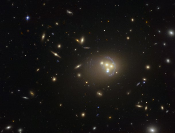 This image from the NASA/ESA Hubble Space Telescope shows the rich galaxy cluster Abell 3827. The strange blue structures surrounding the central galaxies are gravitationally lensed views of a much more distant galaxy behind the cluster. Observations of the central four merging galaxies have provided hints that the dark matter around one of the galaxies is not moving with the galaxy itself, possibly implying dark matter-dark matter interactions of an unknown nature are occuring. Credit: ESO This image from the NASA/ESA Hubble Space Telescope shows the rich galaxy cluster Abell 3827. The strange blue structures surrounding the central galaxies are gravitationally lensed views of a much more distant galaxy behind the cluster. Observations of the central four merging galaxies have provided hints that the dark matter around one of the galaxies is not moving with the galaxy itself, possibly implying dark matter-dark matter interactions of an unknown nature are occuring. Credit: ESO