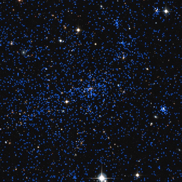 This image superimposes an X-ray image of a distant cluster (the blue pixellated image, from ESA's XMM-Newton satellite) on top of a ground-based view of the sky (from the Canada France Hawaii Telescope). Some of the brightest X-ray objects are galaxies with brilliant centres powered by supermassive black holes. The cluster at the centre of the picture shows up as an extended patch of X-ray emission, coming from hot gas. Credit: ESA/XXL consortium/Canada France Hawaii Telescope This image superimposes an X-ray image of a distant cluster (the blue pixellated image, from ESA's XMM-Newton satellite) on top of a ground-based view of the sky (from the Canada France Hawaii Telescope). Some of the brightest X-ray objects are galaxies with brilliant centres powered by supermassive black holes. The cluster at the centre of the picture shows up as an extended patch of X-ray emission, coming from hot gas. Credit: ESA/XXL consortium/Canada France Hawaii Telescope