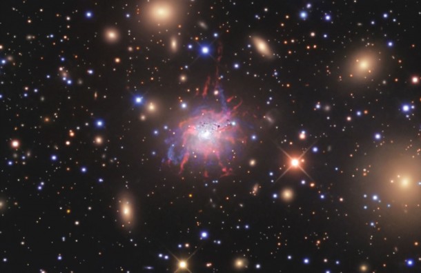 In visible light, the core of the Perseus galaxy cluster looks completely different. The cluster gas so prominent at X-ray wavelengths gives way to a clutch of fuzzy galaxies viewed through a scrim of faint stars in our own. This image shows the same sky area as the Chandra image above. The bizarre object at the center is NGC 1275, the cluster's central galaxy and itself a prominent source of X-ray and radio emission. At the galaxy's core lies a supermassive black hole activated by infalling matter. Glowing filaments extending from the galaxy trace bubbles of gas blown violently outward by the black hole. Despite this activity, Hitomi measurements show that hot cluster gas in the vicinity is moving at cosmically modest speeds. Credits: R. Jay GaBany In visible light, the core of the Perseus galaxy cluster looks completely different. The cluster gas so prominent at X-ray wavelengths gives way to a clutch of fuzzy galaxies viewed through a scrim of faint stars in our own. This image shows the same sky area as the Chandra image above. The bizarre object at the center is NGC 1275, the cluster's central galaxy and itself a prominent source of X-ray and radio emission. At the galaxy's core lies a supermassive black hole activated by infalling matter. Glowing filaments extending from the galaxy trace bubbles of gas blown violently outward by the black hole. Despite this activity, Hitomi measurements show that hot cluster gas in the vicinity is moving at cosmically modest speeds. Credits: R. Jay GaBany