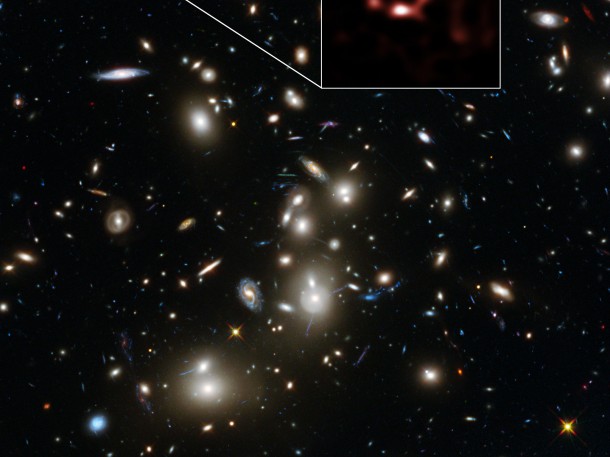 This image is dominated by a spectacular view of the rich galaxy cluster Abell 2744 from the NASA/ESA Hubble Space Telescope. But, far beyond this cluster, and seen when the Universe was only about 600 million years old, is a very faint galaxy called A2744_YD4. New observations of this galaxy with ALMA, shown in red, have demonstrated that it is rich in dust. Credit: ALMA (ESO/NAOJ/NRAO), NASA, ESA, ESO and D. Coe (STScI)/J. Merten (Heidelberg/Bologna) This image is dominated by a spectacular view of the rich galaxy cluster Abell 2744 from the NASA/ESA Hubble Space Telescope. But, far beyond this cluster, and seen when the Universe was only about 600 million years old, is a very faint galaxy called A2744_YD4. New observations of this galaxy with ALMA, shown in red, have demonstrated that it is rich in dust. Credit: ALMA (ESO/NAOJ/NRAO), NASA, ESA, ESO and D. Coe (STScI)/J. Merten (Heidelberg/Bologna)