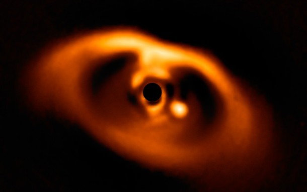 This spectacular image from the SPHERE instrument on ESO's Very Large Telescope is the first clear image of a planet caught in the very act of formation around the dwarf star PDS 70. The planet stands clearly out, visible as a bright point to the right of the centre of the image, which is blacked out by the coronagraph mask used to block the blinding light of the central star. Credit: ESO/A. Müller et al. This spectacular image from the SPHERE instrument on ESO's Very Large Telescope is the first clear image of a planet caught in the very act of formation around the dwarf star PDS 70. The planet stands clearly out, visible as a bright point to the right of the centre of the image, which is blacked out by the coronagraph mask used to block the blinding light of the central star. Credit: ESO/A. Müller et al.